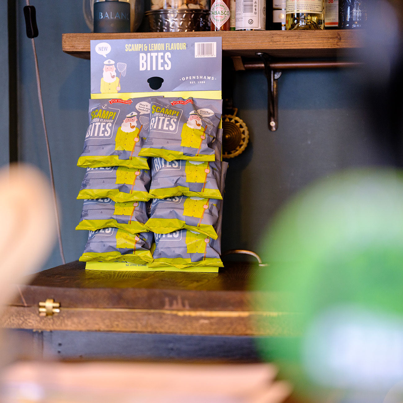 Display of Pub Originals Scampi & Lemon Bites snack packages on a wooden shelf.