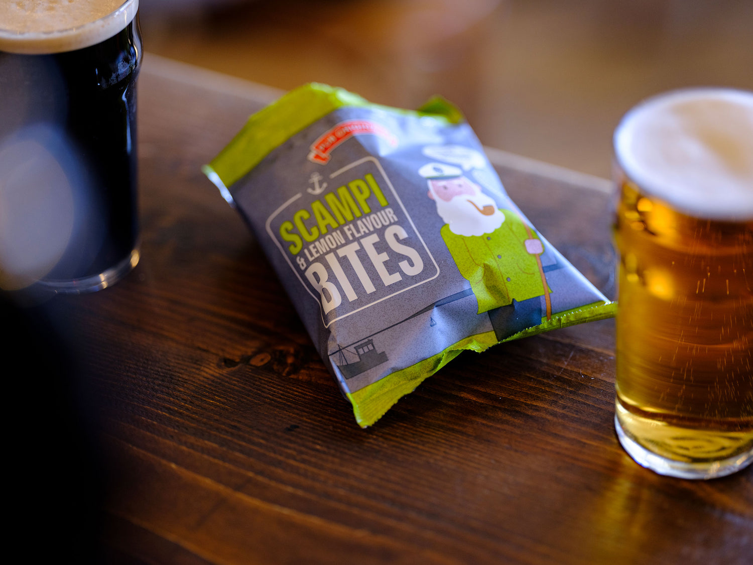 Pub Originals Scampi & Lemon Flavour bites open on a table between two pints of beer.