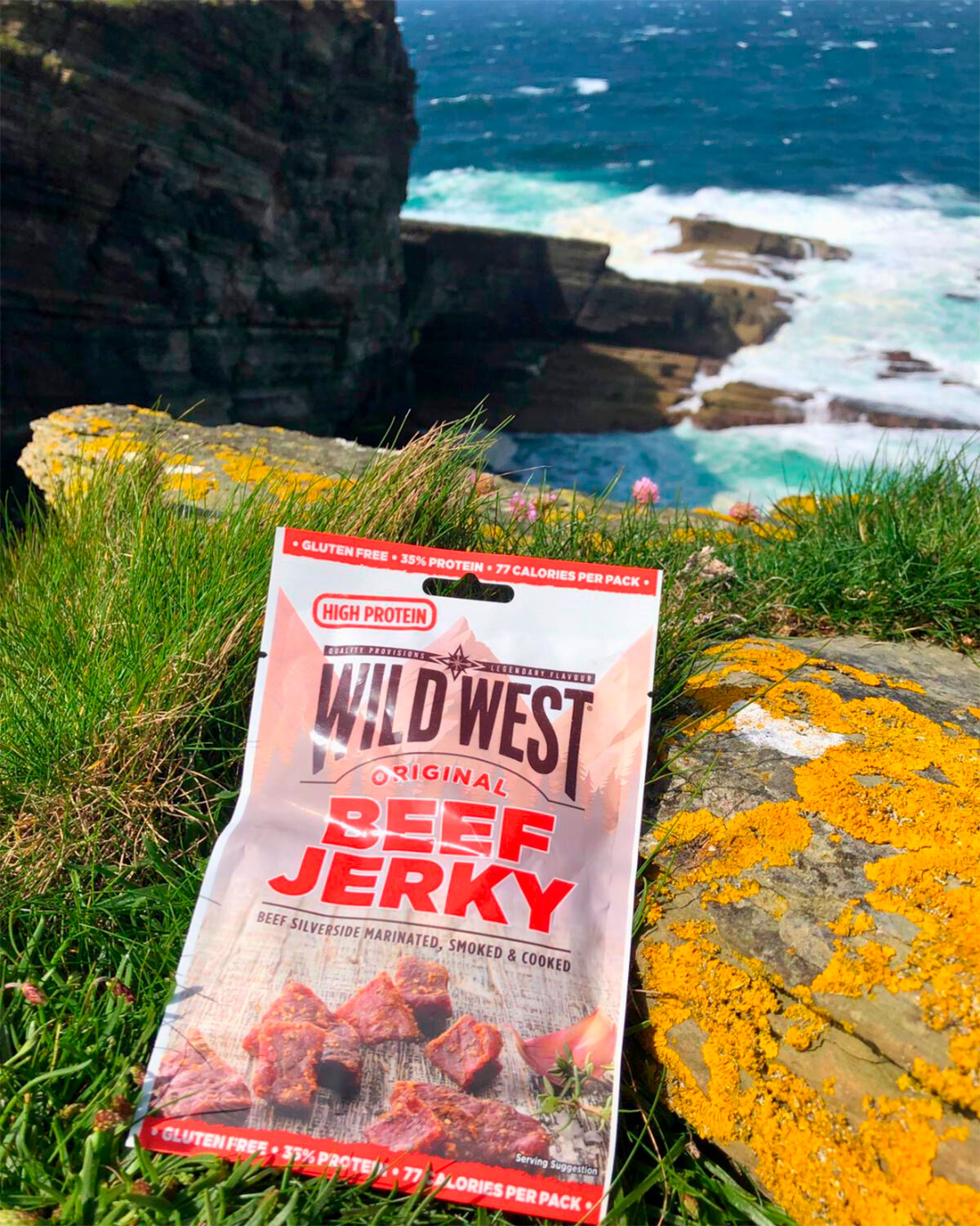 Wild West Beef Jerky package on a rocky cliff with ocean view